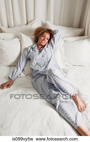 Woman wearing pyjamas reclining in bed View Large Photo Image Stock Photo - Woman wearing pyjamas reclining in bed. Fotosearch