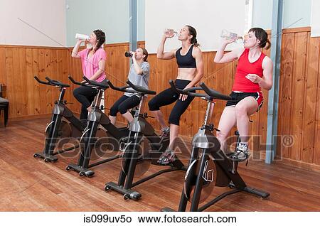 Women on exercise bikes, drinking from bottles View Large Photo Image Picture - Women on exercise bikes, drinking from bottles. Fotosearch