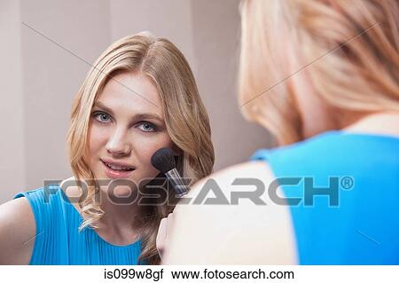 Young woman applying blusher in the mirror View Large Photo Image Stock Image - Young woman applying blusher in the mirror. Fotosearch