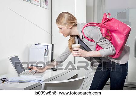 Stock Photograph - Young woman checking emails in office. Fotosearch
