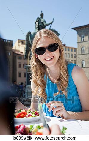 Stock Image - Young woman having salad at restaurant outdoors. Fotosearch