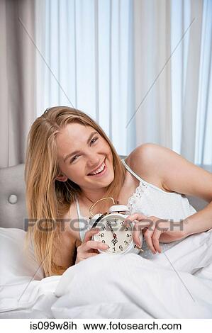 Young woman holding alarm clock View Large Photo Image Stock Image - Young woman holding alarm clock. Fotosearch