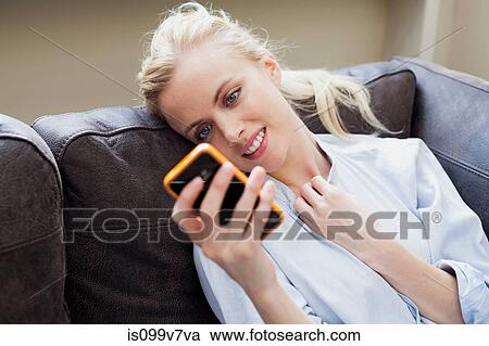 Young woman looking at smartphone and smiling View Large Photo Image Stock Image - Young woman looking at smartphone and smiling. Fotosearch