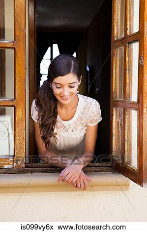 Stock Photo - Young woman looking out of window. Fotosearch