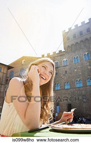 Young woman on cellphone at restaurant outdoors View Large Photo Image Picture - Young woman on cellphone at restaurant outdoors. Fotosearch