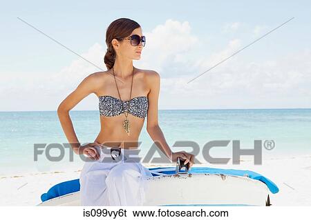 Young woman sitting on boat on beach View Large Photo Image Stock Photograph - Young woman sitting on boat on beach. Fotosearch