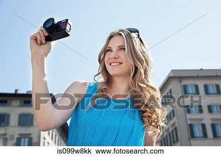 Stock Image - Young woman using vintage camera. Fotosearch