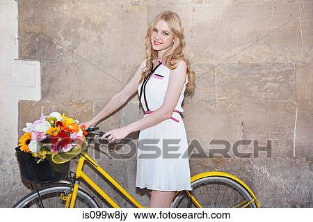 Young woman with flowers in basket of bicycle View Large Photo Image Stock Photo - Young woman with flowers in basket of bicycle. Fotosearch