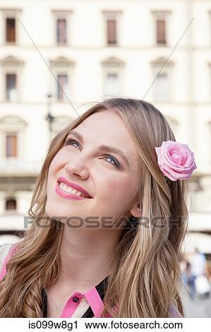 Stock Image - Young woman with pink rose in her hair. Fotosearch
