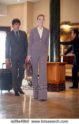 Stock Image - Business people walking in hotel lobby. Fotosearch