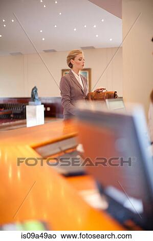 Picture - Businesswoman checking into hotel. Fotosearch