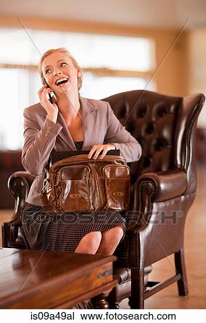 Stock Image - Businesswoman on cell phone in lobby. Fotosearch