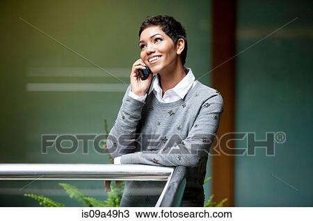 Stock Image - Businesswoman talking on phone in office. Fotosearch