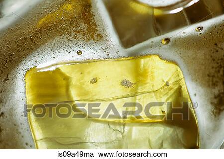 Stock Image - Close up of ice cubes in glass of beer. Fotosearch