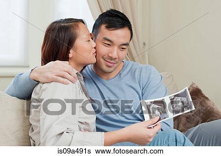 Couple examining sonogram on sofa View Large Photo Image Stock Photograph - Couple examining sonogram on sofa. Fotosearch