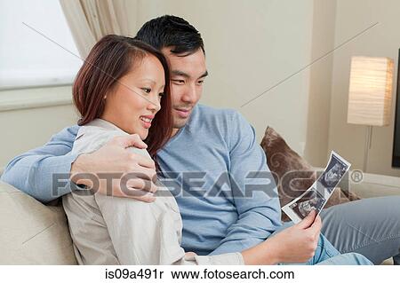 Couple examining sonogram on sofa View Large Photo Image Stock Photography - Couple examining sonogram on sofa. Fotosearch