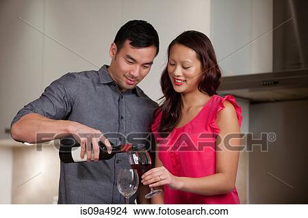 Picture - Couple having wine together in kitchen. Fotosearch