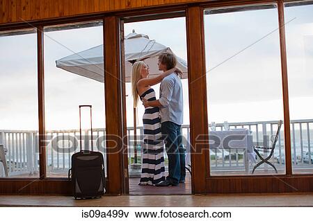Stock Photo - Couple hugging on beachfront patio. Fotosearch