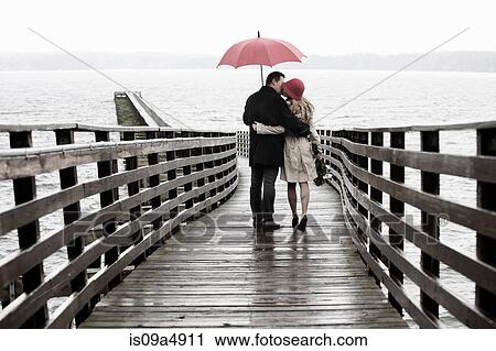 Couple kissing on wooden pier in rain View Large Photo Image Stock Image - Couple kissing on wooden pier in rain. Fotosearch