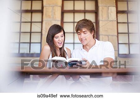 Stock Image - Couple reading travel book together. Fotosearch