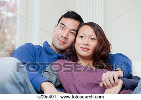 Stock Image - Couple relaxing together on sofa. Fotosearch