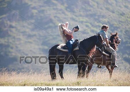 Stock Image - Couple riding horses in rural landscape. Fotosearch