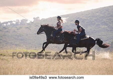 Stock Image - Couple riding horses in rural landscape. Fotosearch