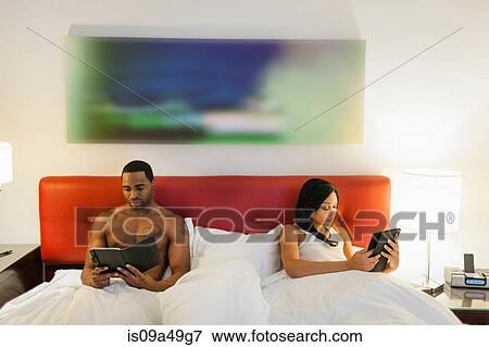 Stock Photo - Couple using e-readers in bed. Fotosearch