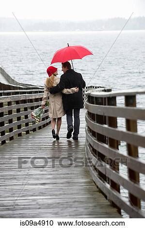 Couple walking on wooden pier in rain View Large Photo Image Stock Image - Couple walking on wooden pier in rain. Fotosearch