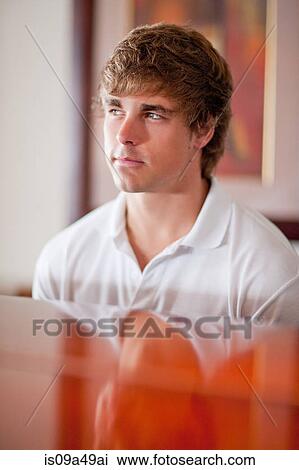 Stock Image - Frowning man sitting at piano. Fotosearch