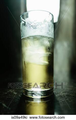Stock Image - Glass of beer illuminated on bar. Fotosearch