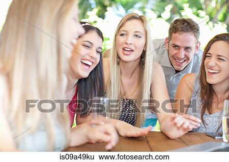 Stock Photograph - Group of friends talking at table. Fotosearch