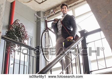 Man carrying bicycle down staircase View Large Photo Image Stock Image - Man carrying bicycle down staircase. Fotosearch