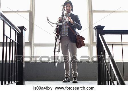 Man carrying bicycle on staircase View Large Photo Image Stock Photo - Man carrying bicycle on staircase. Fotosearch