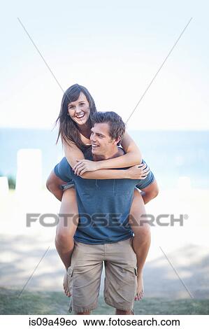 Man carrying girlfriend on beach View Large Photo Image Picture - Man carrying girlfriend on beach. Fotosearch