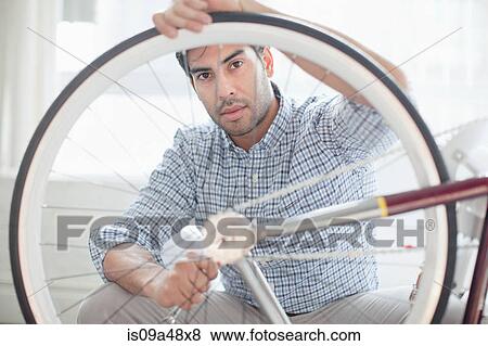 Man fixing bicycle wheel indoors View Large Photo Image Stock Photo - Man fixing bicycle wheel indoors. Fotosearch