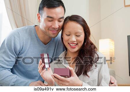 Stock Photo - Man giving girlfriend gift on sofa. Fotosearch