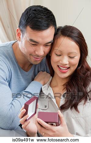 Stock Photo - Man giving girlfriend gift on sofa. Fotosearch