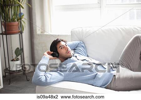 Man listening to headphones on sofa View Large Photo Image Stock Image - Man listening to headphones on sofa. Fotosearch