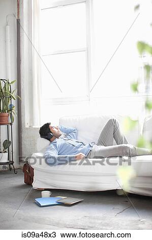 Man listening to headphones on sofa View Large Photo Image Stock Image - Man listening to headphones on sofa. Fotosearch