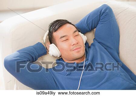Man listening to headphones on sofa View Large Photo Image Stock Photo - Man listening to headphones on sofa. Fotosearch
