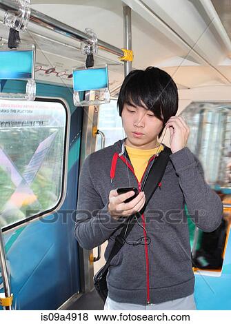 Stock Photo - Man listening to mp3 player on bus. Fotosearch