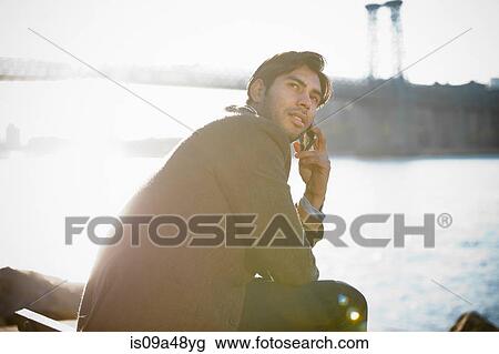 Stock Image - Man on cell phone by urban bridge. Fotosearch