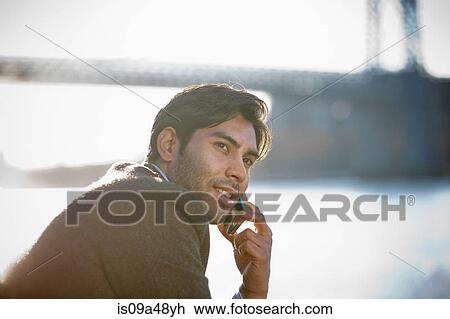 Stock Image - Man on cell phone by urban bridge. Fotosearch