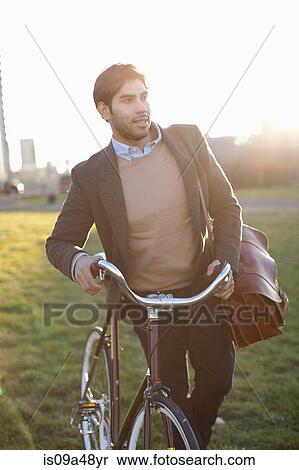 Man pushing bicycle in grass View Large Photo Image Stock Photography - Man pushing bicycle in grass. Fotosearch