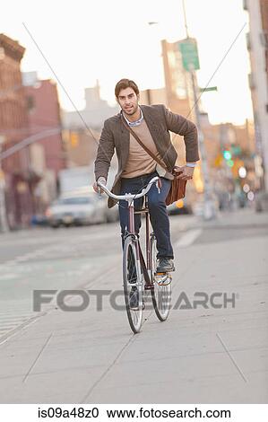 Stock Image - Man riding bicycle on city street. Fotosearch