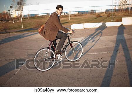 Stock Photo - Man riding bicycle on city street. Fotosearch
