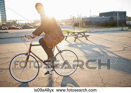 Man riding bicycle on city street View Large Photo Image Stock Photo - Man riding bicycle on city street. Fotosearch