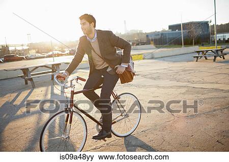 Man riding bicycle on city street View Large Photo Image Stock Photo - Man riding bicycle on city street. Fotosearch