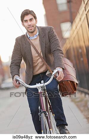 Man riding bicycle on city street View Large Photo Image Stock Photo - Man riding bicycle on city street. Fotosearch